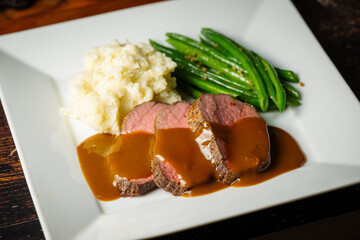  pouring brown gravy sauce on roasted beef