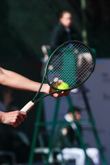 Detail of young boy with racket playing tennis on a clay court during a university tournament. the athlete is wearing a blue sports t-shirt and is preparing to serve for set point