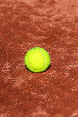 Detail of a tennis ball stopped on the ground of a clay tennis court during a sunny day