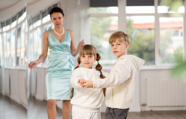 Small passionate ballroom enthusiasts, tween girl and boy practicing graceful waltz routine in...