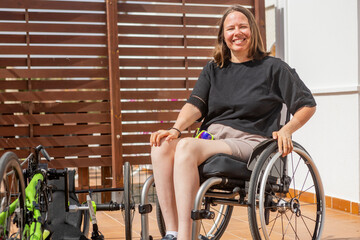 Smiling woman in a wheelchair next to her handbike