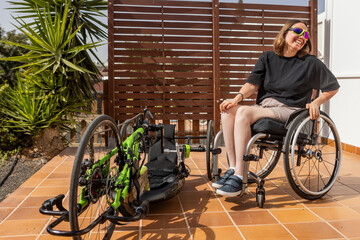 Confident woman with handbike and wheelchair