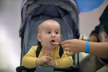 a one-year-old child, a boy, eats on the road, has a snack on the way in a stroller
