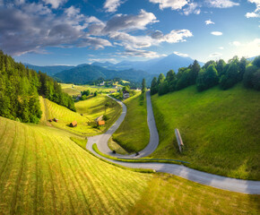 Aerial view of country road in green meadows at sunset in summer