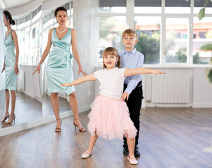 Motivated preteen ballroom dancers, girl and boy in performance outfit practicing elegant dance...