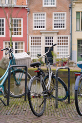 Fototapeta na wymiar Picturesque Netherlands. Bicycles parked alongside a channel on beautiful old buildings background.