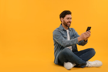 Happy man with smartphone on yellow background. Space for text