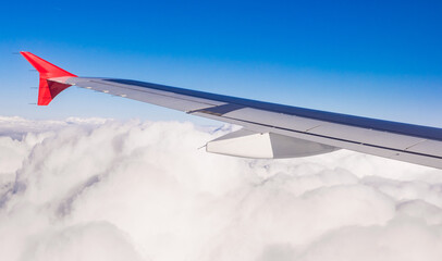 wing of airplane above fluffly clouds  - 770100978