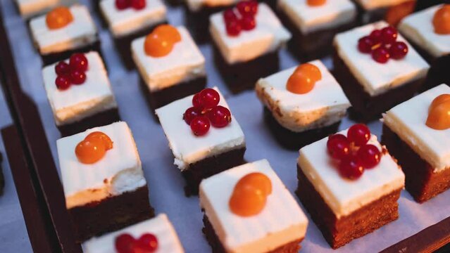 Beautiful multicolored decorated baked sweet tasty candy bar dessert selection with cake, pie and pastries catering banquet table on a kids children party, coffee break buffet at a conference