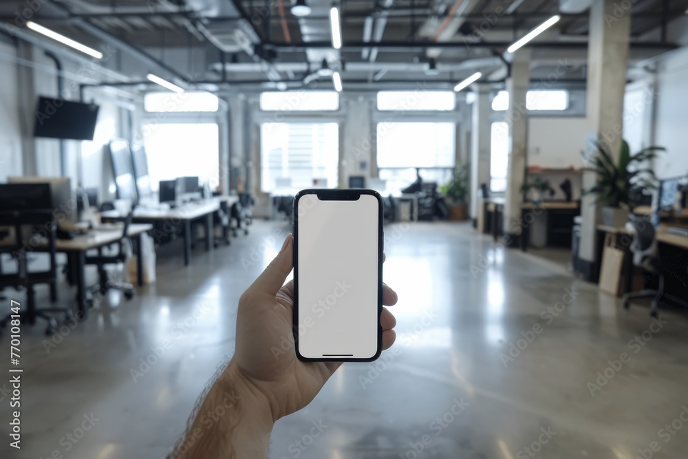 Aufkleber An individual holding a smartphone with a blank screen in a contemporary open office workspace environment