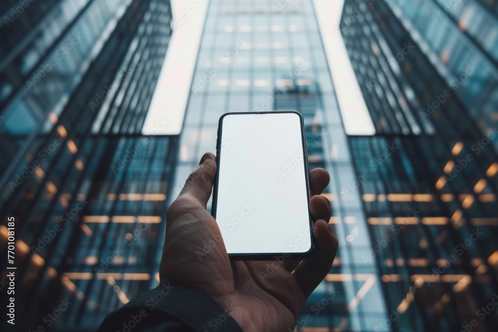 Aufkleber a person's hand displays a smartphone with a blank screen in front of towering glass skyscrapers, si