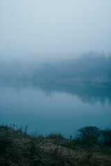 Foggy frost lake . Landscape with fog . Mystery nature . Blue hour . Morning at winter .
