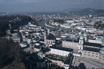 Aerial view of a European city with historic buildings and a river cutting through, under a cloudy sky.