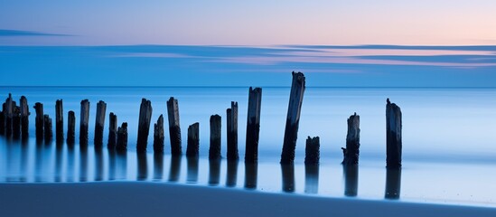Wooden breakwaters in the sea at sunset. Long exposure. - obrazy, fototapety, plakaty