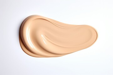 A creamy swatch of makeup is elegantly smeared against a smooth, neutral-toned backdrop.