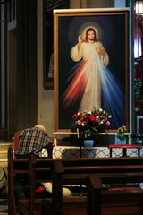 A man praying in front of a painting of the divine Jesus