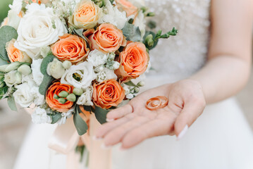 Obraz na płótnie Canvas bride holds wedding rings and bouquet