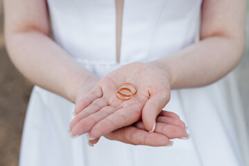 bride holds wedding rings in hands