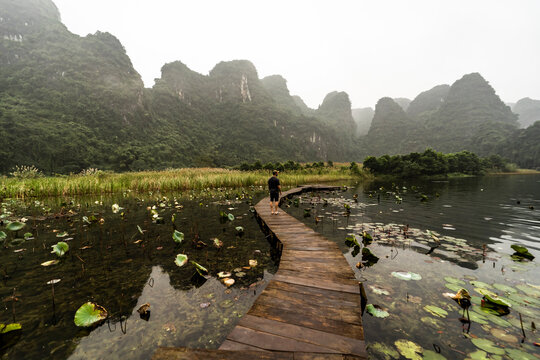 Serene lake scene with wooden path in foggy Vietnamese landscape