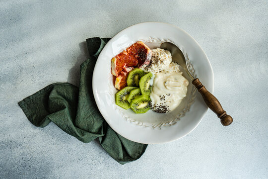 Top view of start your day right with this healthful bowl of natural yogurt, cottage cheese, chia seeds, and freshly sliced kiwi and Sicilian orange