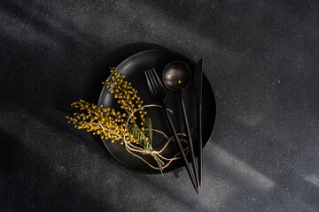 Elegant black dinnerware set with vibrant mimosa flowers
