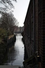 Tranquil canal between old brick buildings at dusk, reflecting a serene urban atmosphere.