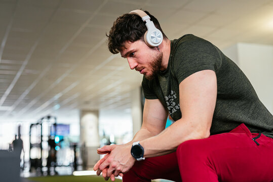 Determined thoughtful young man resting during gym workout