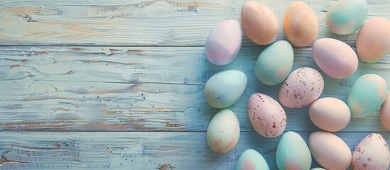 Obraz premium Pastel Easter eggs in an array of colors are displayed on a wooden board background, with empty space around them. The image has a vintage tone to it.