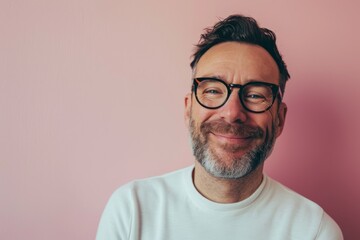 Portrait of a handsome middle-aged man with a beard and glasses on a pink background - obrazy, fototapety, plakaty