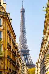 The Eiffel Tower stands tall against a clear blue sky, framed by the traditional buildings of a Parisian street. Paris, France