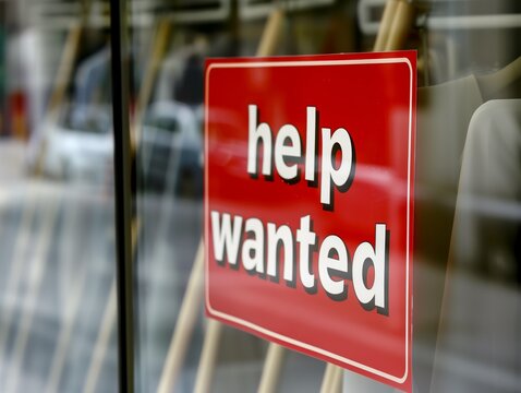 A red sign that says "Help Wanted" is hanging on a window