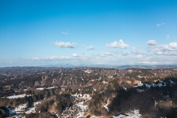 ドローン写真：雪が溶けつつある田舎の山と、広がる青空と雲
