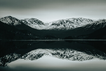 snowing mountain and lake reflection panorama in Norway