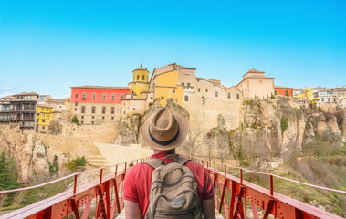 Hipster travelier man with backpack looking at panoramic view of Cuenca old town city in Spain - Tourist visit the colorful hanging houses -Travel and wanderlust concept.