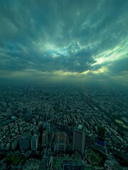 Dramatic aerial view of a cityscape under stormy skies with sunbeams piercing through clouds.