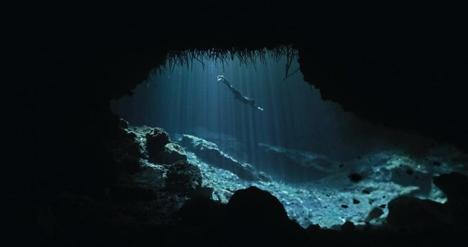 Majestic view of a diver in a cave with sun rays passing through