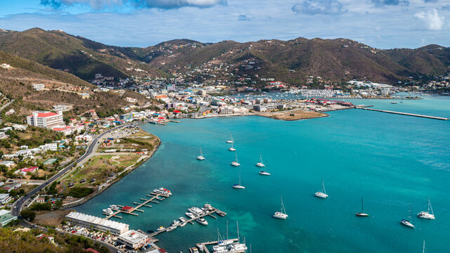 An aerial view showcases a vibrant harbor in the British Virgin Islands, where sailboats dot the turquoise sea