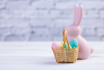 Easter composition with a pink rabbit figurine and a basket with candies.