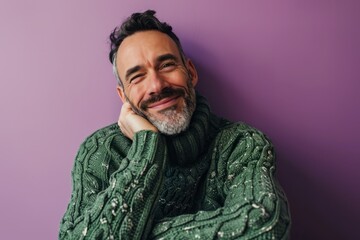 Portrait of a handsome bearded man in a warm green sweater on a purple background
