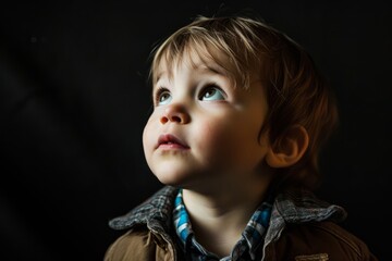 Portrait of a beautiful little boy on a dark background. Close-up.