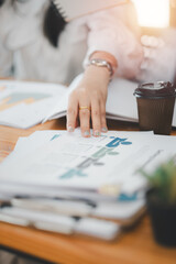 Close up of a business professional hand resting on a stack of financial documents, implying...