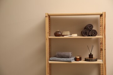 Soft towels, candles, air freshener and spa products on shelves indoors. Space for text