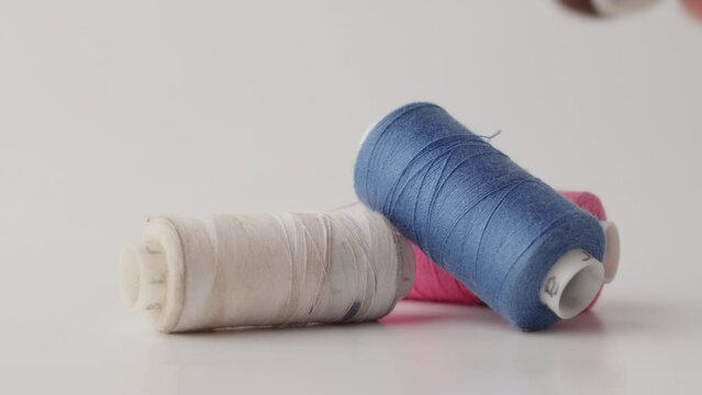 Hand Picking Up Sewing Thread Spools On White Background, Close Up