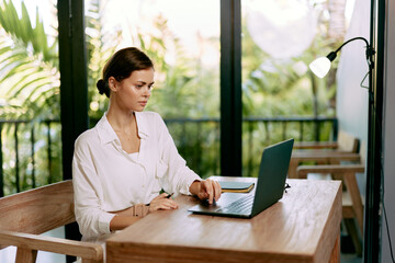 Happy woman working on her laptop at her home office The cozy and stylish workspace showcases her...