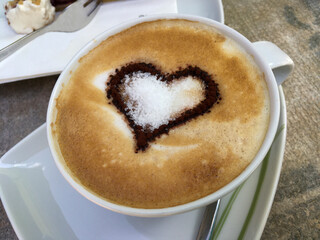 Cappuccino mit einem Kakao Herz auf verziertem Milchschaum