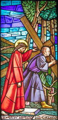 MILAN, ITALY - MARCH 48 2024: The Simon of Cyrene helps Jesus carry the cross on the stained glass in the church Chiesa di San Gregorio Barbarigo from 20. cent. 