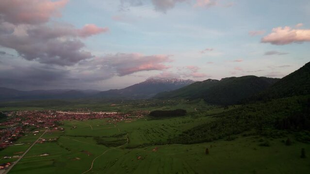 Aerial shot of Zarnesti at sunset with lush fields and distant mountains