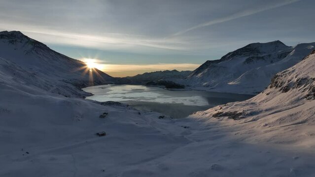 Splendid sun apparition on frozen lake in snowy mountains at dawn