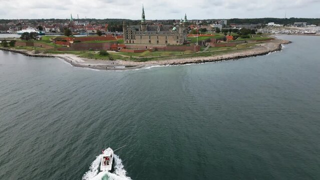 motorboat sailing on the sea, huge castle directly on the coast, kronborg slot, baltic sea, helsingor, denmark, europe, drone