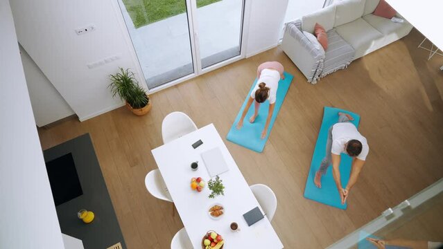 Fit Sporty Middle Aged Couple Doing Yoga At Home. Senior Healthy Mature Man And Woman Standing In Yoga Pose Enjoying Morning Training Exercises In Modern House Living Room. Top View From Above.